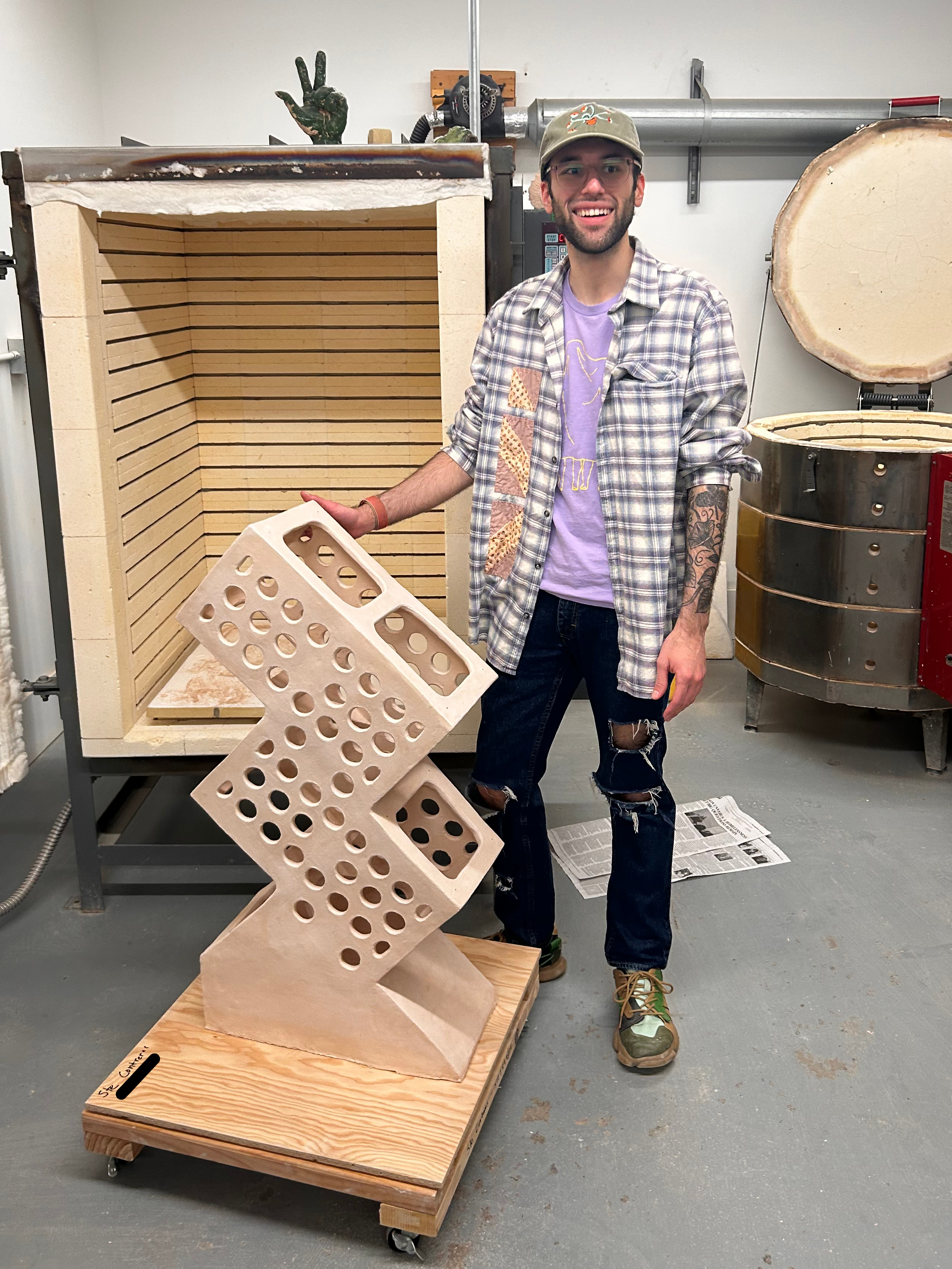 Ste Contreras standing in front of a kiln with a sculpture
